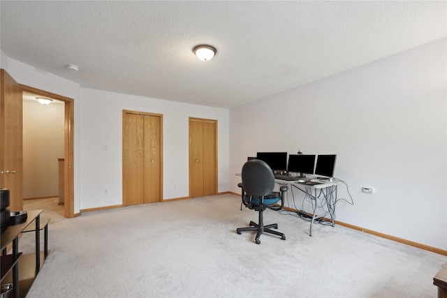 home office with a textured ceiling, baseboards, and light carpet
