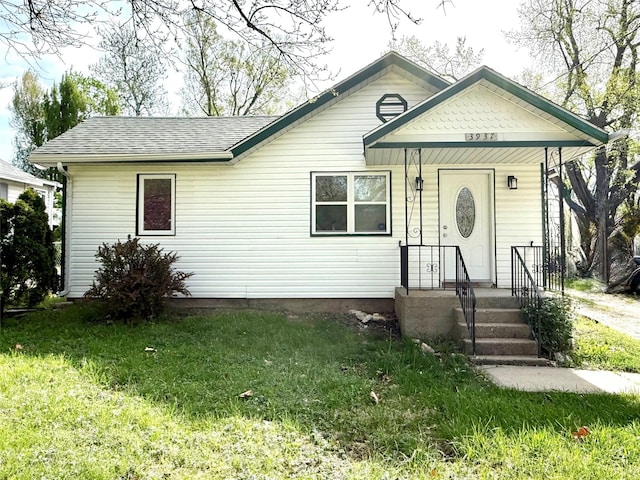 view of front facade featuring a shingled roof and a front lawn