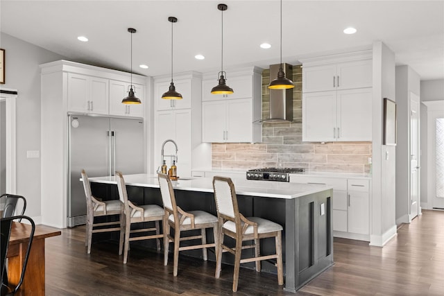 5129 NE Seneca Dr, Ankeny, IA 50021 - kitchen featuring stainless steel built in fridge, wall chimney range hood, decorative backsplash, light countertops, and an island with sink