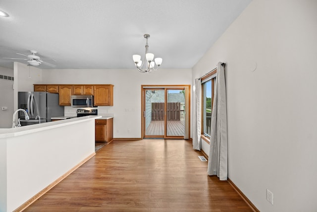 5099 Clover Ridge Rd, Panora, IA 50216 - kitchen with light wood-style floors, brown cabinets, decorative light fixtures, and stainless steel appliances