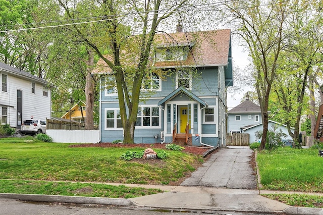 american foursquare style home with fence and a front lawn