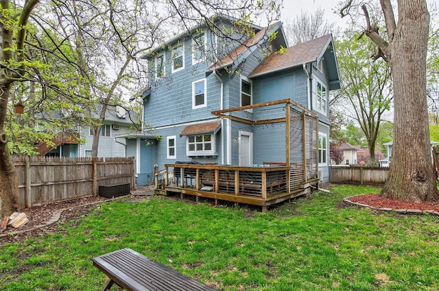 back of house featuring a fenced backyard, a lawn, and a deck