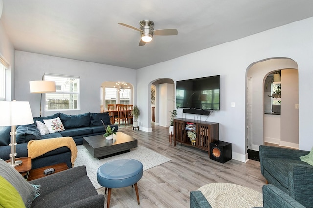 living area featuring arched walkways, ceiling fan, baseboards, and wood finished floors