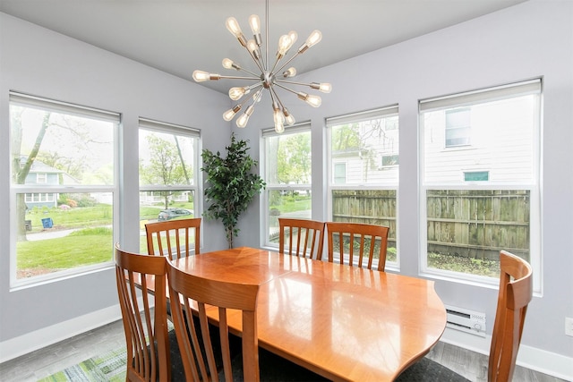 dining room featuring baseboards, a baseboard heating unit, wood finished floors, and a notable chandelier