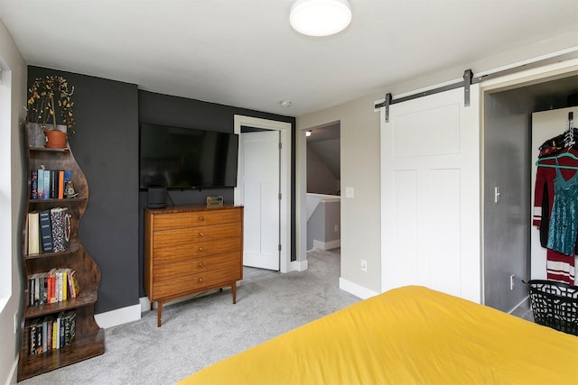 bedroom with carpet floors, a barn door, and baseboards