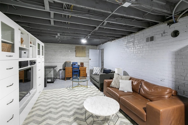 living area with carpet floors, brick wall, and visible vents