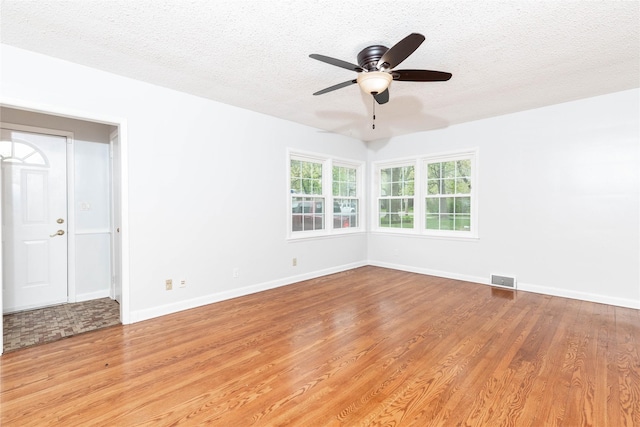 spare room with ceiling fan, a textured ceiling, visible vents, light wood-type flooring, and baseboards