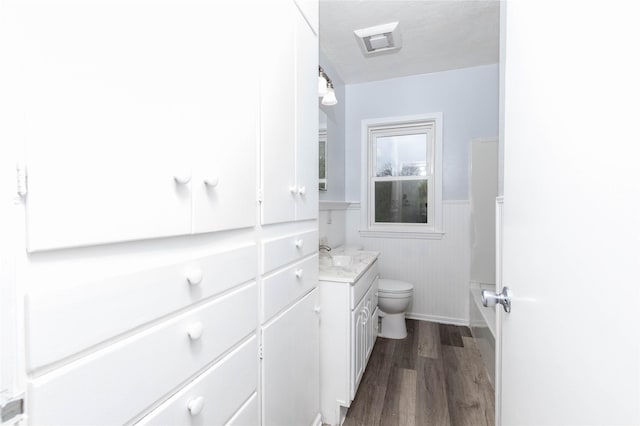bathroom with vanity, wood finished floors, toilet, and a wainscoted wall