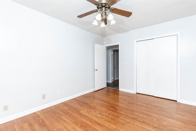 unfurnished bedroom featuring baseboards, light wood finished floors, ceiling fan, and a closet