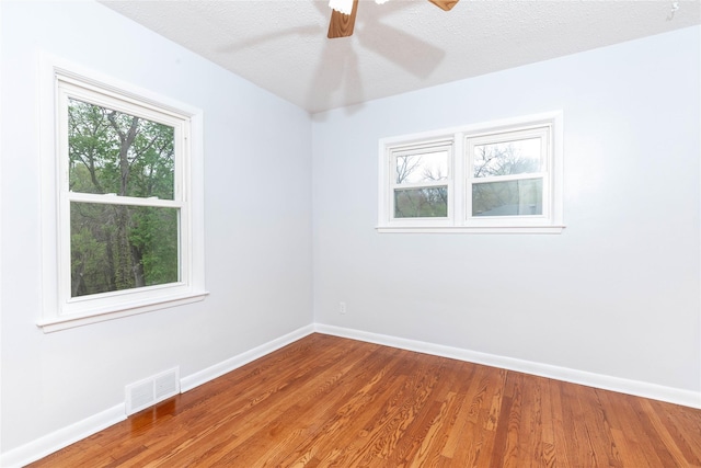 unfurnished room featuring baseboards, ceiling fan, wood finished floors, and visible vents