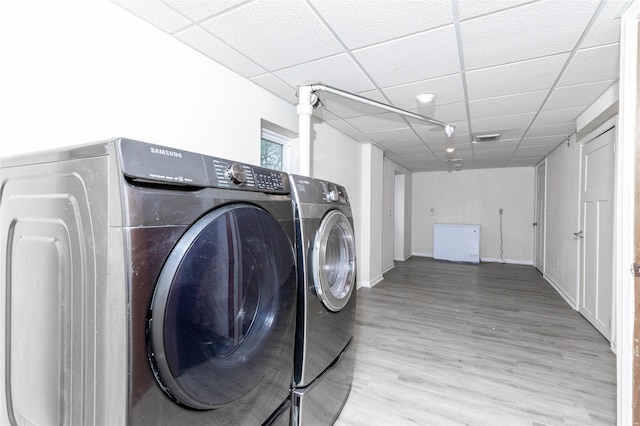 clothes washing area with laundry area, wood finished floors, and washing machine and clothes dryer