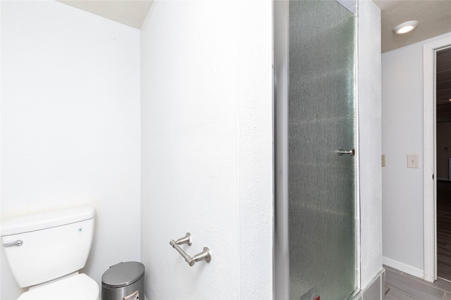 full bath featuring toilet, baseboards, a shower stall, and wood finished floors