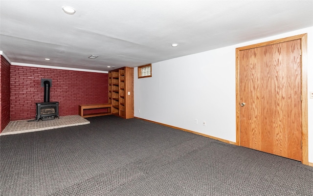 finished below grade area featuring dark colored carpet, a wood stove, baseboards, and recessed lighting