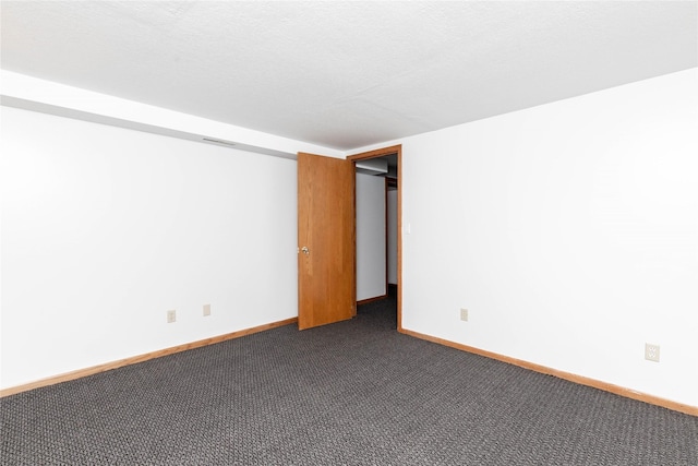 empty room with baseboards, visible vents, and dark colored carpet