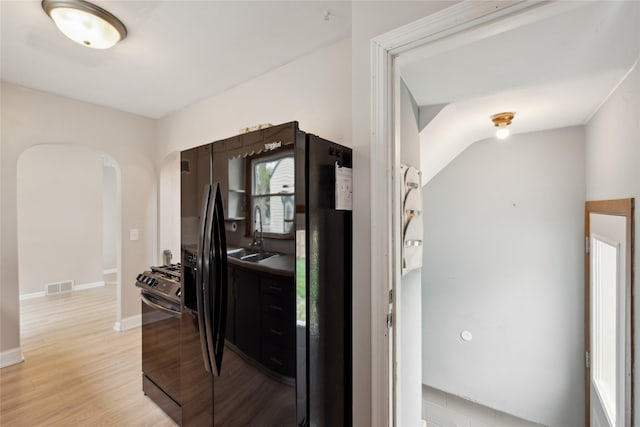 corridor featuring visible vents, arched walkways, light wood finished floors, and baseboards
