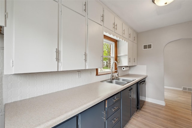 kitchen with a sink, white cabinets, black dishwasher, and visible vents