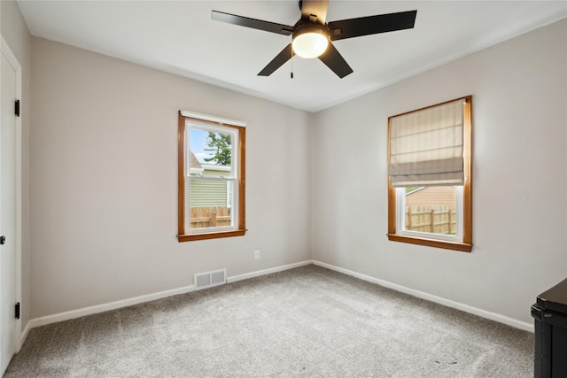 carpeted empty room with baseboards, ceiling fan, and visible vents