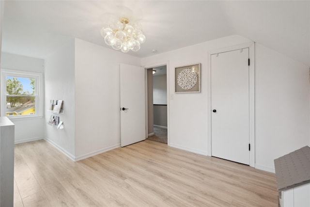unfurnished bedroom with baseboards, an inviting chandelier, and light wood-type flooring