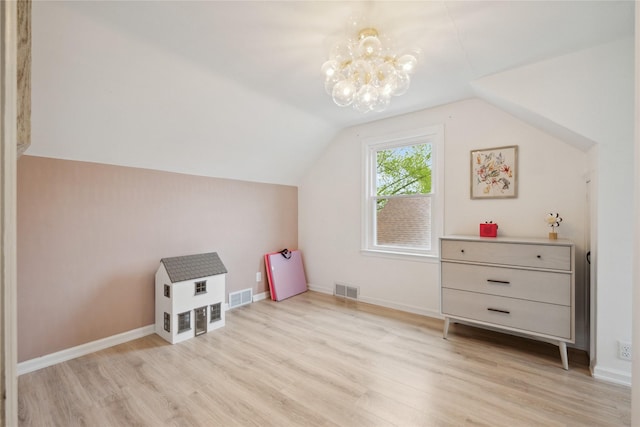 additional living space with visible vents, light wood-style flooring, vaulted ceiling, and an inviting chandelier