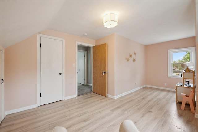 interior space with baseboards, light wood-style flooring, and lofted ceiling