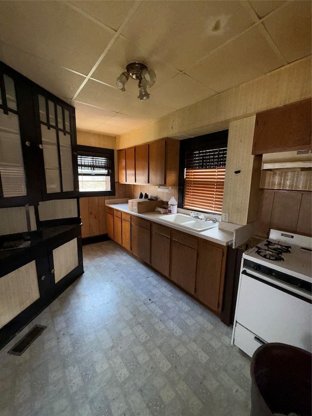 kitchen with a paneled ceiling, visible vents, gas range gas stove, light floors, and under cabinet range hood