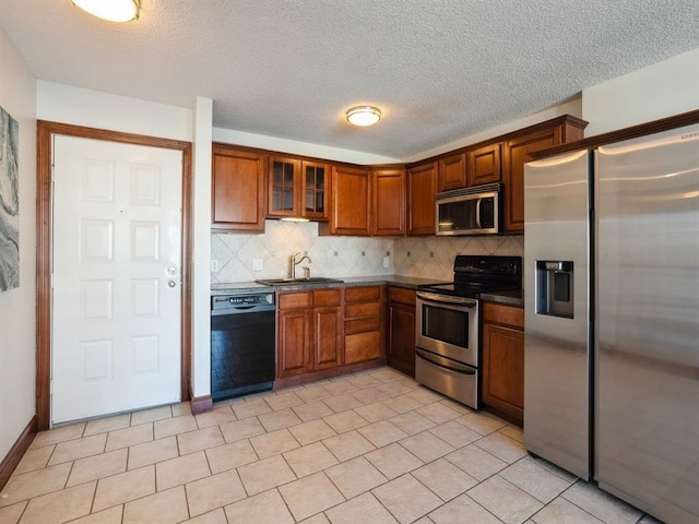 300 Walnut St Unit 1407, Des Moines, IA 50309 - kitchen featuring appliances with stainless steel finishes, dark countertops, decorative backsplash, brown cabinets, and a textured ceiling