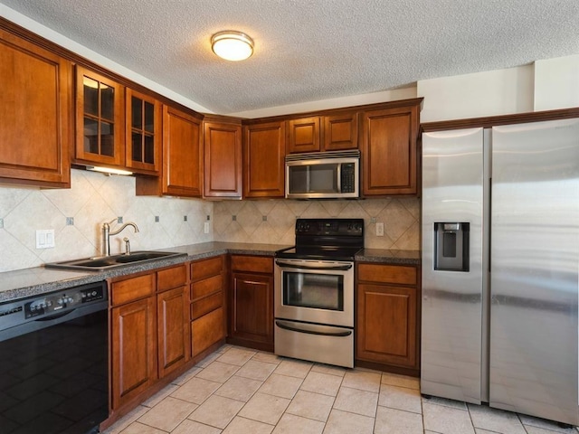300 Walnut St Unit 1407, Des Moines, IA 50309 - kitchen with stainless steel appliances, a textured ceiling, dark countertops, light tile patterned flooring, and glass insert cabinets