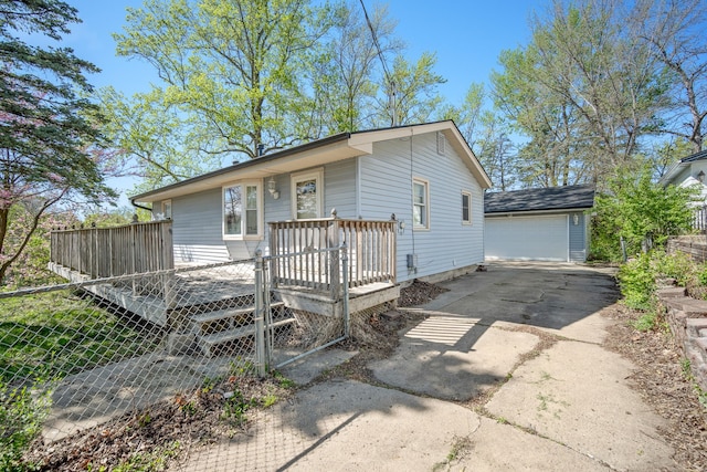 view of front of home featuring a detached garage, a deck, fence, and an outdoor structure