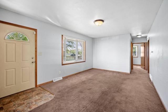 entryway with carpet flooring, baseboards, and visible vents