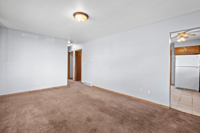 spare room with visible vents, baseboards, ceiling fan, and light carpet