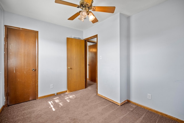 unfurnished bedroom featuring baseboards, visible vents, ceiling fan, and carpet