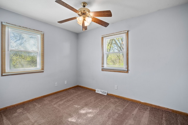 carpeted spare room with baseboards, a ceiling fan, and visible vents
