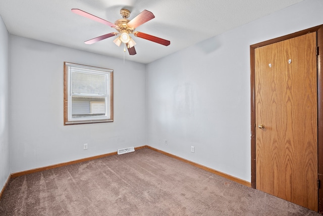 unfurnished room with carpet flooring, baseboards, visible vents, and ceiling fan