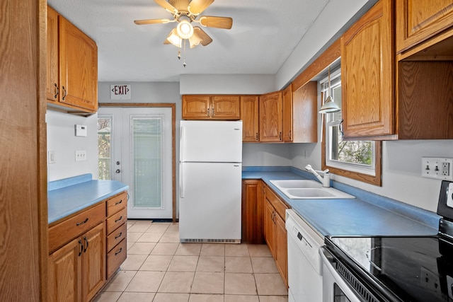 kitchen featuring brown cabinetry, a ceiling fan, white appliances, a sink, and light tile patterned floors