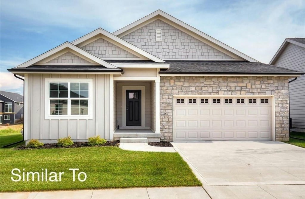view of front of home with board and batten siding, a front yard, concrete driveway, an attached garage, and stone siding