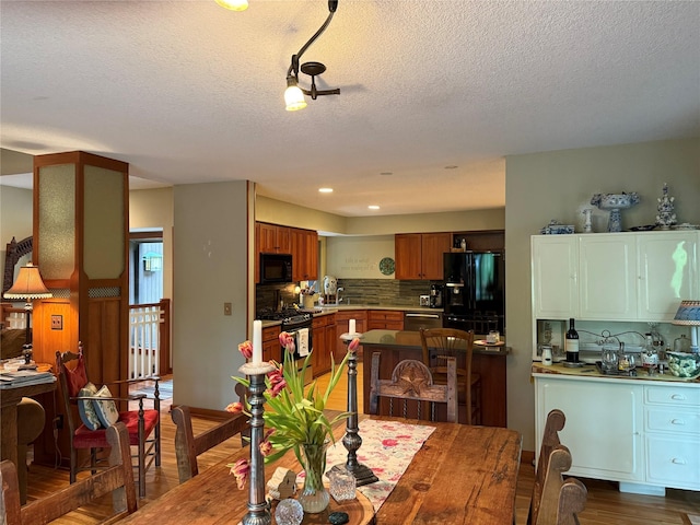 dining space with a textured ceiling, recessed lighting, and wood finished floors