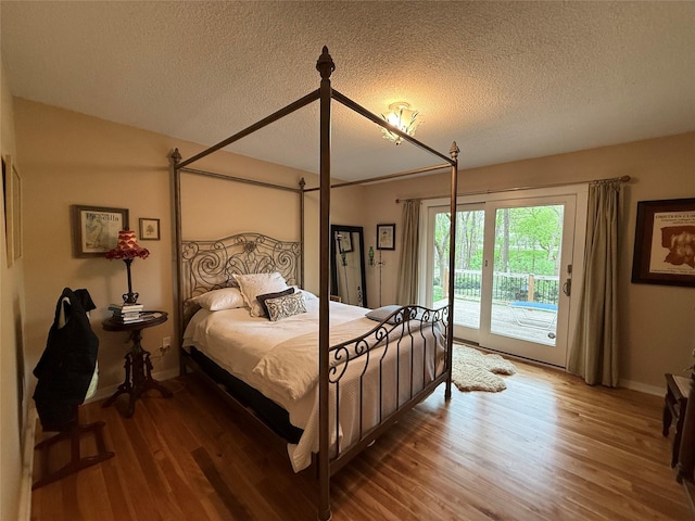bedroom with baseboards, access to outside, a textured ceiling, and wood finished floors
