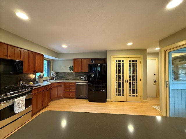 kitchen featuring french doors, a sink, light wood finished floors, and black appliances