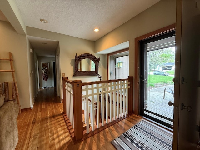 interior space with a textured ceiling, baseboards, recessed lighting, and wood finished floors