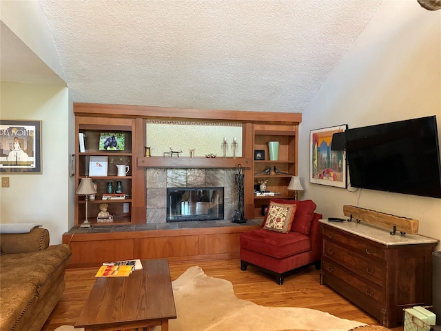 living room with a fireplace, a textured ceiling, and light wood-style floors