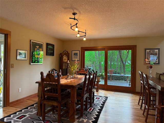 956 55th St, West Des Moines, IA 50266 - dining space with light wood-style floors, track lighting, a textured ceiling, and baseboards