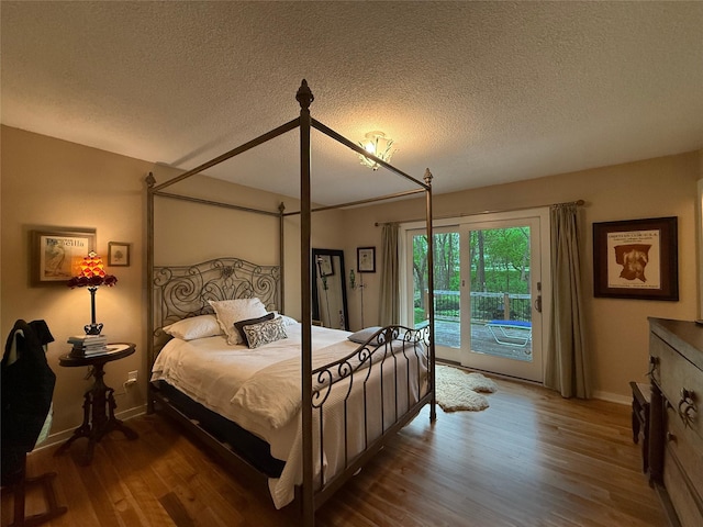 956 55th St, West Des Moines, IA 50266 - bedroom with a textured ceiling, wood finished floors, access to exterior, and baseboards
