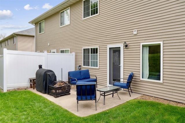back of property with a lawn, an outdoor living space with a fire pit, a patio area, and fence