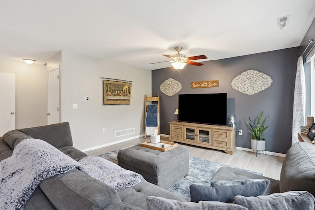 living area with baseboards, a ceiling fan, wood finished floors, and visible vents