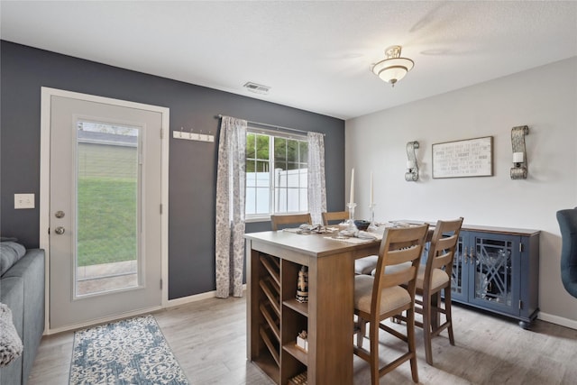 dining area with light wood-style floors, baseboards, and visible vents