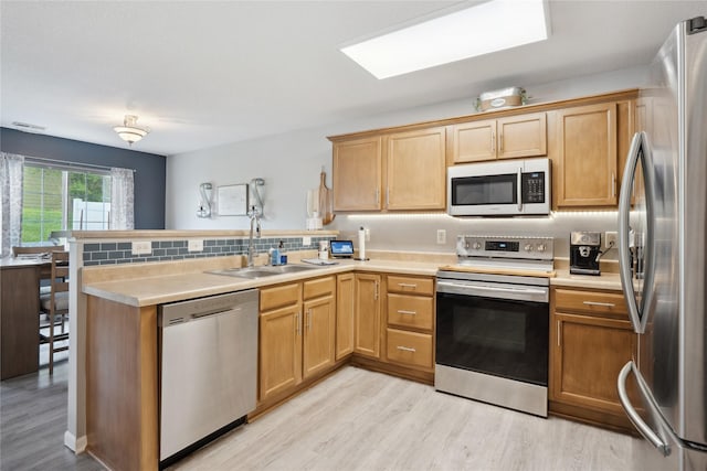 kitchen featuring light countertops, stainless steel appliances, light wood-style floors, and a peninsula
