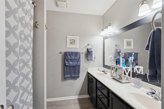 bathroom featuring visible vents, a sink, baseboards, and double vanity