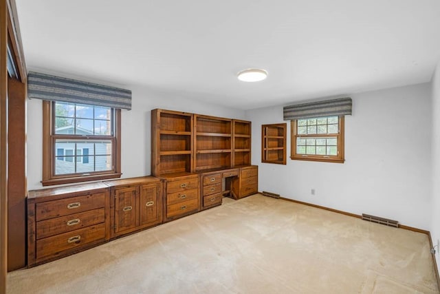 unfurnished office featuring visible vents, baseboards, plenty of natural light, and light colored carpet