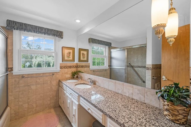 bathroom featuring a sink, tile patterned floors, double vanity, and tile walls