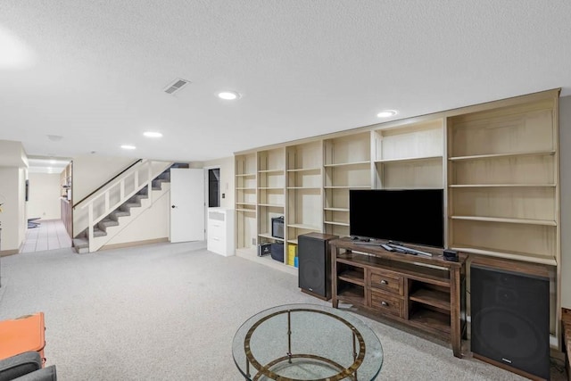 unfurnished living room with carpet floors, stairs, a textured ceiling, and visible vents